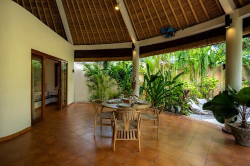 a dining room with a table and chairs at Flor Villa by Betterplace in Dalung