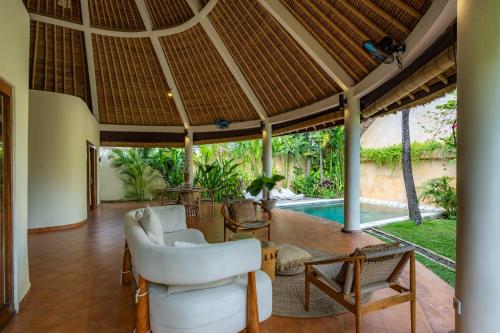 an open living room with a white couch and chairs at Flor Villa by Betterplace in Dalung