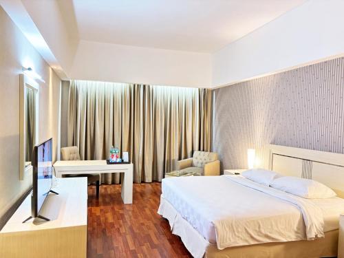 a hotel room with a bed and a television at Grand Elite Hotel Pekanbaru in Pekanbaru
