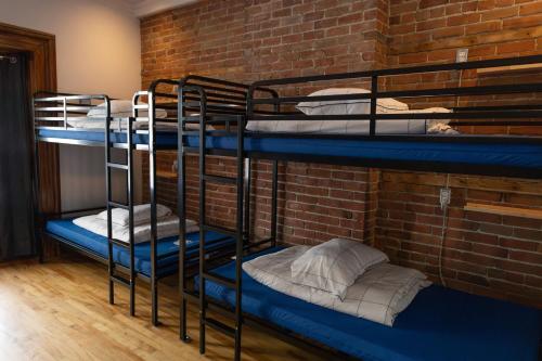 a room with three bunk beds in a brick wall at Auberge Le Treehouse in Montreal