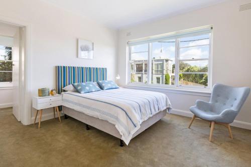 a bedroom with a bed and a chair and a window at Beach Belle Mornington in Mornington