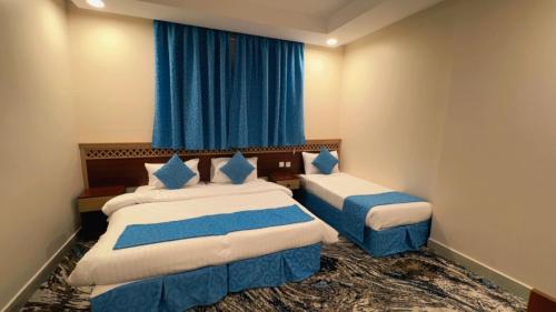a hotel room with two beds and blue curtains at فندق الروضة المتحدة Hotel AL Rawdah United in Al Khansāk