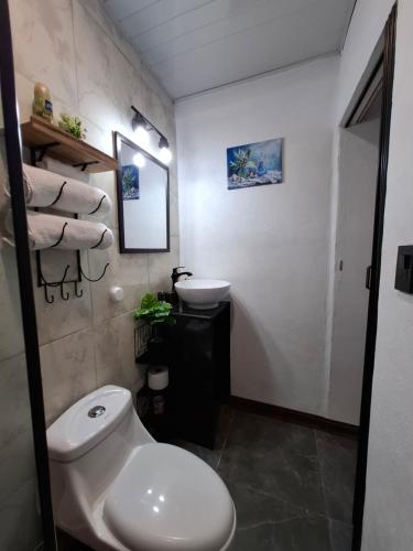 a bathroom with a white toilet and a sink at Forest Love in Quepos