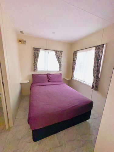 a bedroom with a purple bed and two windows at Macquarie Caravan Park in Warren