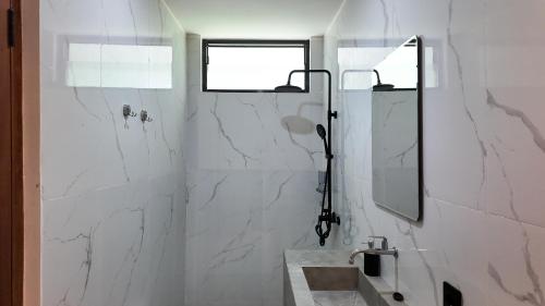 a white bathroom with a sink and a mirror at Pulau Indah Lombok in Kuta Lombok