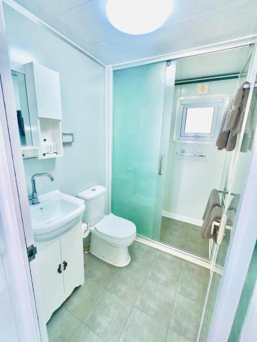 a bathroom with a toilet and a glass shower at Macquarie Caravan Park in Warren