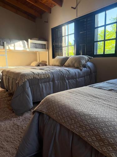 two beds in a room with two windows at Loft del centro Saladillo in Saladillo
