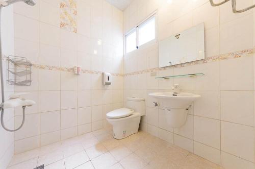 a white bathroom with a toilet and a sink at Maji Homestay in Taitung City