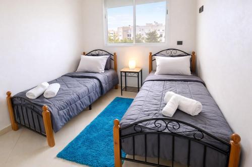 two twin beds in a room with a window at Spacious Family-Friendly Apartment in Temara