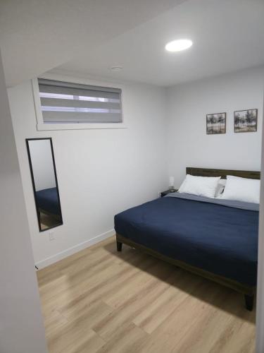 a bedroom with a blue bed and a mirror at Mayfair Suite in Airdrie