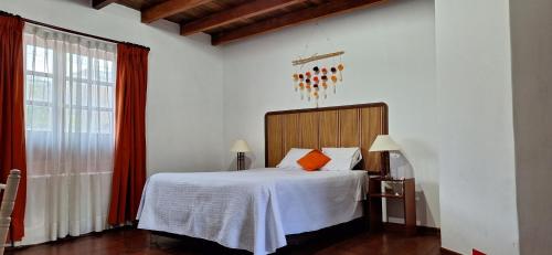 a bedroom with a bed with white sheets and orange pillows at Casa Wayra Cajamarca in Cajamarca