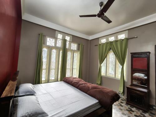 a bedroom with a bed with green curtains and a fan at Prashaanti in Guwahati