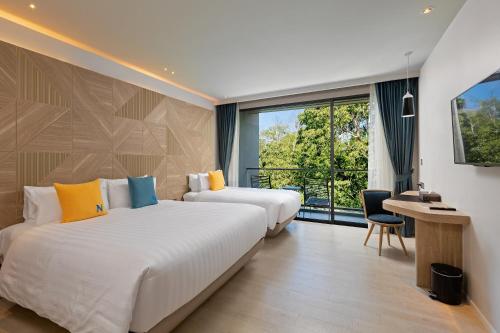 a hotel room with two beds and a window at The Nature Phuket in Patong Beach