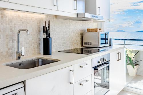 a white kitchen with a sink and a view of the ocean at CP - Modern Beachside Apartment in Estepona in Estepona