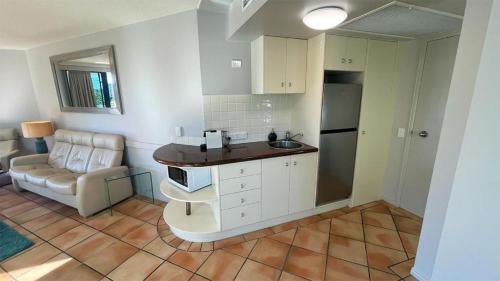 a kitchen with a sink and a couch in a room at La Promenade Absolute Waterfront Apartments in Caloundra