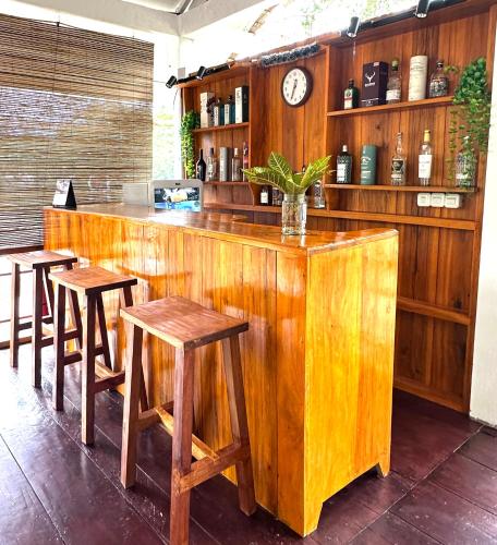 a wooden bar with stools and a clock at joe Dive resort in Pulau Lembeh