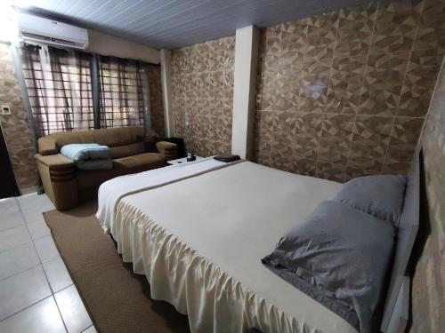 a bedroom with a large bed and a couch at Alojamiento familiar cerca del Aeropuerto - SKYHOME FAMILY - Luque in Nu Guazu