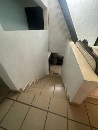 an attic room with a staircase and a tiled floor at Cuarto a 4min del aeropuerto in Guadalajara
