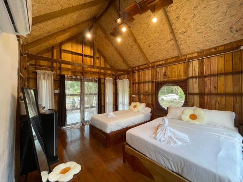 a bedroom with two beds in a wooden cabin at Baanraipoonwana Baanwanason in Ban Nong Hu