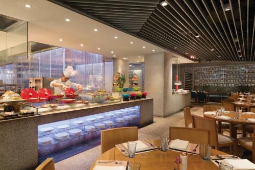 a restaurant with tables and a chef preparing food at Shangri-La Qingdao - May Fourth Square in Qingdao