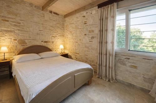 a bedroom with a bed and a stone wall at Mersini Village in Milonianá