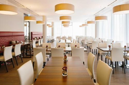 a dining room with tables and white chairs at Chester Hotel Heidelberg in Heidelberg