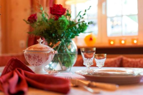 a table with a vase of roses and a plate and glasses at Landhausvilla Strittberg 7 in Höchenschwand