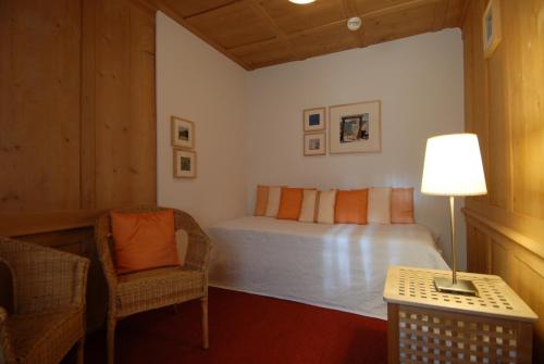 a bedroom with a bed and a chair and a lamp at Hotel Ducan in Monstein