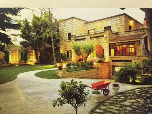 a large brick house with a red wagon in front of it at Beit Wadih in Ghazīr