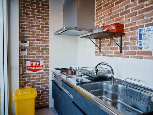 a kitchen with a sink and a brick wall at THE BOXY AWAJI in Awaji