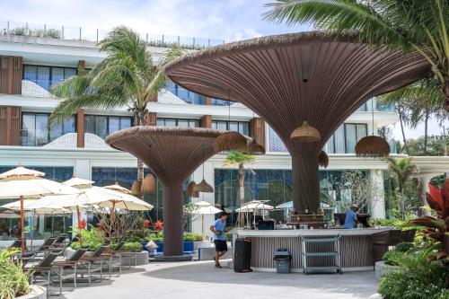a resort with large brown umbrellas in a courtyard at The Sunshine Beach Resort Studio in Layan Beach