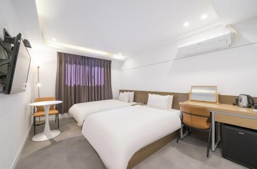 ein Hotelzimmer mit zwei Betten und einem Schreibtisch in der Unterkunft Busan Hauendae Ark Blue Hotel in Busan