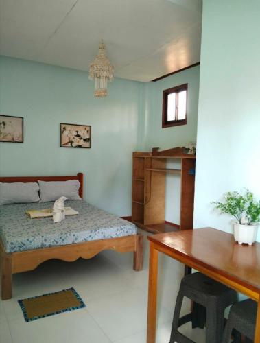 a room with a bed and a desk and a table at Jenises Inn in El Nido