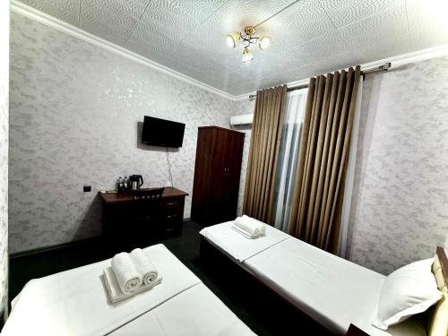 a hotel room with two beds and a desk at Hafiz Plaza Hotel in Tashkent