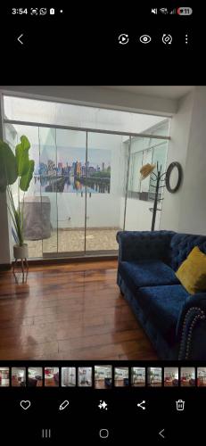 a living room with a blue couch and a large window at Depa Excelente Vintage in La Molina
