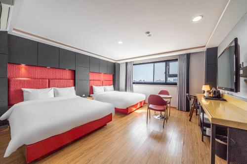 a hotel room with two beds and a desk at Hotel memory Jumunjin- Welcome drink provided in Gangneung