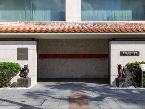 a building with two statues in front of it at JR Kyushu Hotel Blossom Naha in Naha