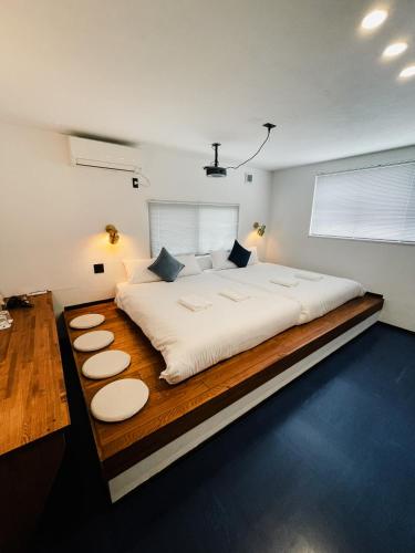 a bedroom with a large white bed with a wooden floor at Bridge33 CAFE AND HOSTEL in Takagi
