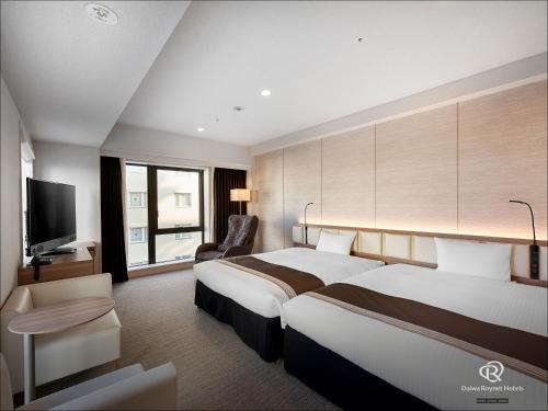 a hotel room with two beds and a flat screen tv at Daiwa Roynet Hotel Okinawa-Kenchomae in Naha