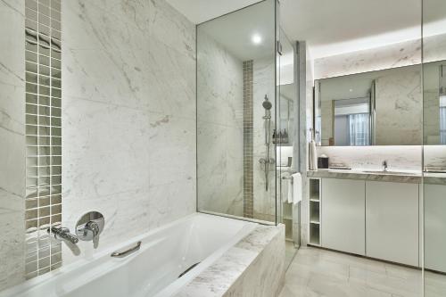 a white bathroom with a tub and a sink at Grand Copthorne Waterfront Hotel Singapore in Singapore