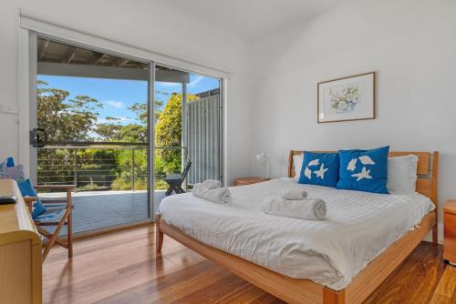 a bedroom with a bed and a large window at Hyams Reflections Hyams Beach in Hyams Beach