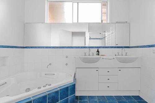 a white bathroom with two sinks and a tub at Hyams Reflections Hyams Beach in Hyams Beach