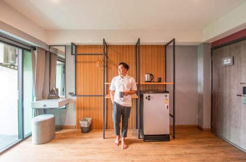 a man standing in a kitchen next to a refrigerator at Lima Hotel in Phra Nakhon Si Ayutthaya