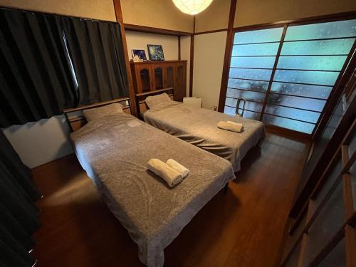 two beds in a bedroom with two towels on them at ほしのすみか in Nikko