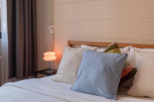 ein Schlafzimmer mit einem Bett, Kissen und einer Lampe in der Unterkunft Walk2BTS, KingBed, FastWiFi, FreeLaundry, Netflix in Klong Toi