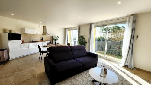 a living room with a couch and a table at La maison des Vignes est climatisée avec ménage, draps et serviettes inclus in Tabanac