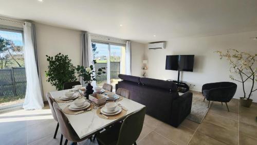 a living room with a table and a couch at La maison des Vignes est climatisée avec ménage, draps et serviettes inclus in Tabanac
