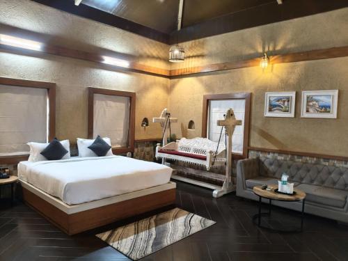 a bedroom with a large bed and a couch at Vaikunth Village Resort in Raipur