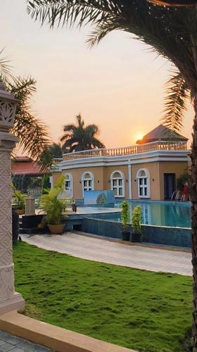a large house with a swimming pool and palm trees at Vaikunth Village Resort in Raipur