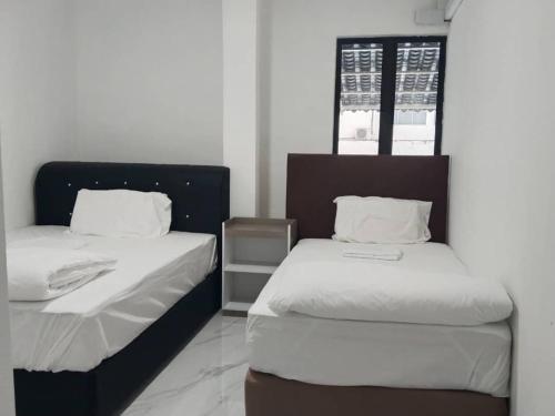 a room with two beds with white sheets at H Sri Sayang Hotel Sdn Bhd in Skudai